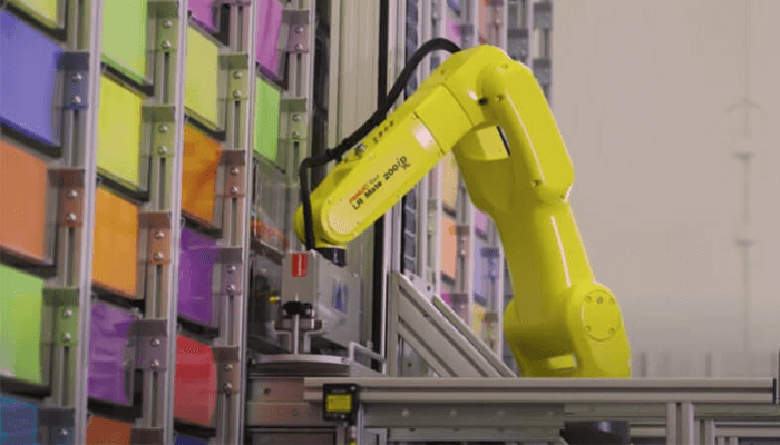A yellow FANUC Robot sorting a storage facility.
