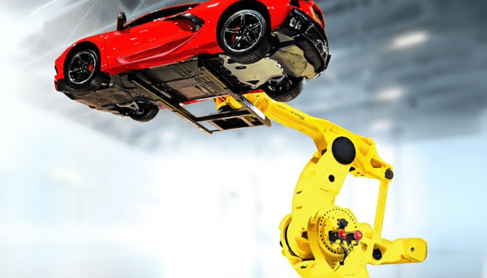 A yellow FANUC robot lift holding up a red car.