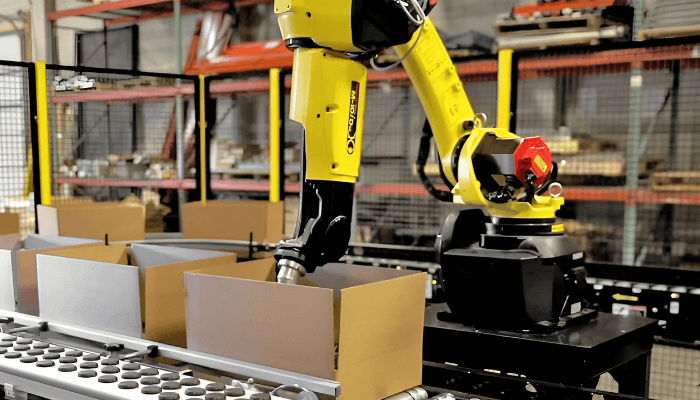 A yellow FANUC robotic performing logistics packaging. 